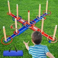 a young boy playing with an outdoor game set on the grass in front of him