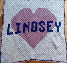 a crocheted heart with the word lindsey written in blue on it