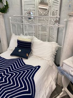 a white bed topped with a blue and white blanket