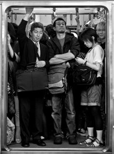 black and white photograph of people standing in subway car with their arms around each other