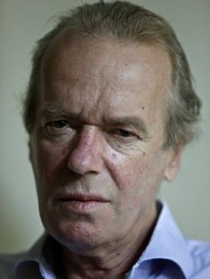 an older man wearing a blue shirt and looking at the camera with a serious look on his face