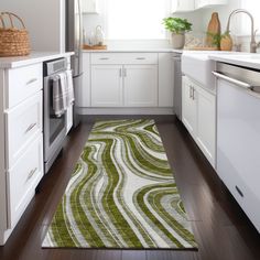 a kitchen with white cabinets and green rugs on the wooden floor next to an oven