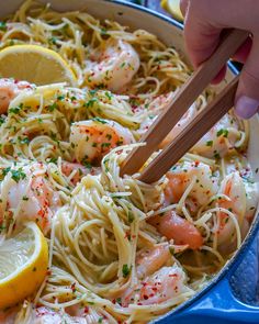 someone using chopsticks to eat pasta with shrimp and lemon