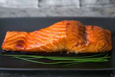 a piece of salmon sitting on top of a black plate