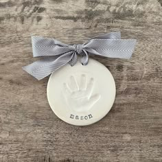 a white ceramic ornament with a hand print on it and a ribbon tied around the top