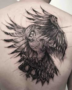 the back of a man's shoulder with an owl and key tattoo on it