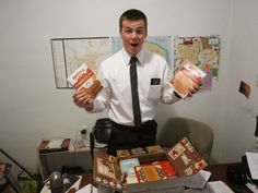 a man holding two boxes of food in his hands and making a surprised face while standing next to a desk