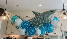 a shark net hanging from the ceiling in a kitchen with blue and white balloons attached to it