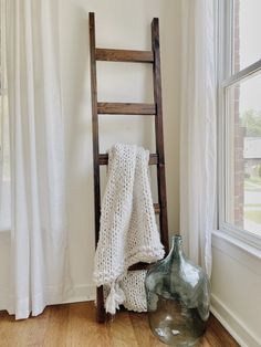 a ladder leaning against a wall next to a vase with a white blanket on it