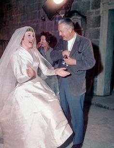 a man and woman dressed in wedding attire dance together on the sidewalk at night time