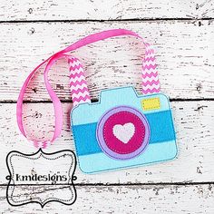 a camera with a heart on it is hanging from a pink and blue leasher