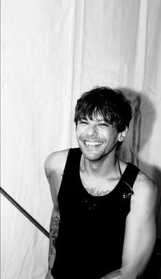 black and white photograph of a man with tattoos on his arm smiling at the camera