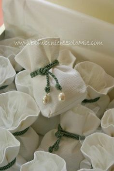 a box filled with lots of white cloth covered in green string and pearls on top of it