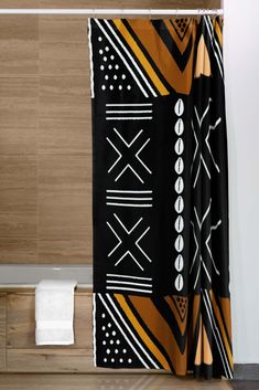 a black and yellow shower curtain hanging on the side of a bathtub next to a toilet