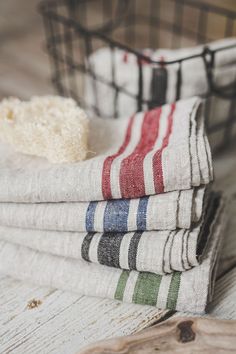 four folded towels sitting on top of a wooden table next to a basket filled with rice