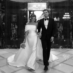 a man and woman in formal wear are walking through the lobby holding each other's hands