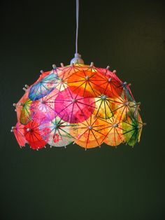 a multicolored umbrella hanging from a light fixture in a room with green walls