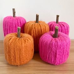 three yarn pumpkins sitting on top of a wooden table