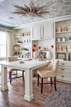 a dining room table with two chairs and a chandelier hanging from the ceiling