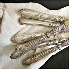 three antique silverware sitting on top of a white cloth