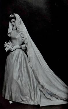 an old black and white photo of a woman in a wedding dress with her veil pulled back