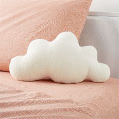 a white cloud pillow sitting on top of a bed next to a pink pillow cover