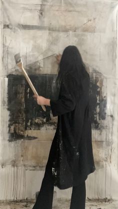 a woman with long hair holding a paintbrush in her hand and painting on the wall