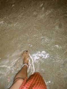 a person standing in the water with their feet up