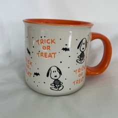 an orange and white coffee mug with trick or treat on it's side is sitting in front of a white background