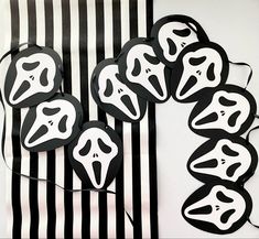 black and white striped paper with ghost masks on it's sides, in front of a wall