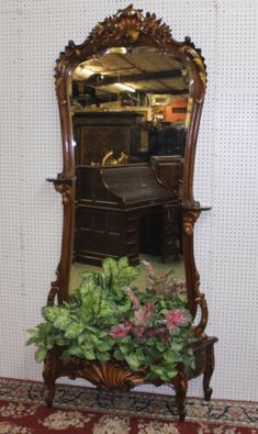 an antique wooden desk and mirror with potted plants