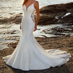 a woman standing on top of a beach next to the ocean wearing a wedding dress