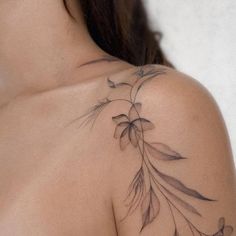 the back of a woman's shoulder with flowers on it and leaves around her neck