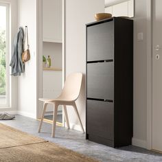 a white chair sitting next to a black cabinet in a living room with a rug on the floor