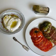 a plate with tomatoes, an egg and some other food on it next to a knife and fork