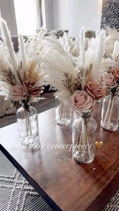 vases with flowers and feathers are sitting on a table in front of a couch