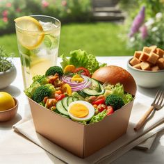 an open box filled with lots of food on top of a table next to bowls and utensils