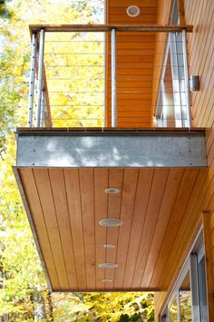 an outdoor balcony with stairs leading up to the upper floor and above it is a wooden deck