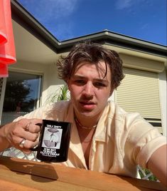 a man sitting at a table with a coffee mug in front of him and an object on the table next to him