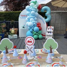 the table is set up for an outdoor birthday party with balloons and paper hats on it