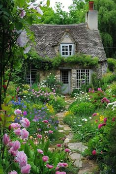 an old stone cottage surrounded by flowers and greenery