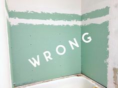 a bathtub with the word wrong painted on it's wall in a bathroom