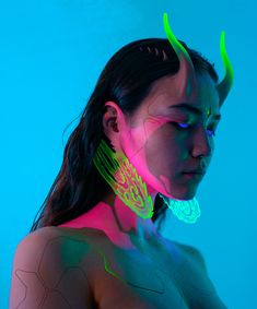 a woman with neon makeup and horns on her head is standing in front of a blue background