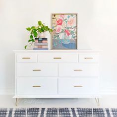 a white dresser with flowers and books on top