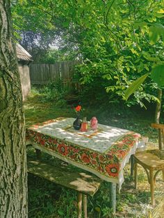 a picnic table with two vases on it in the middle of a yard next to a tree