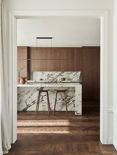 an open kitchen with marble counter tops and stools