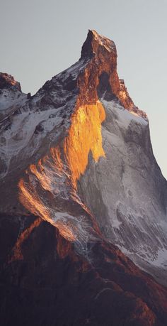 the top of a snow covered mountain in the evening sun with an orange glow on it's face