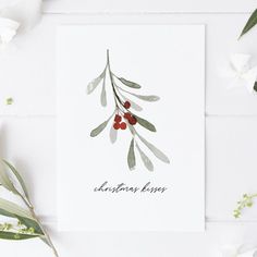 a card with the words christmas kisses written on it next to flowers and greenery