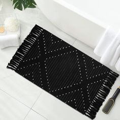 a black rug with white dots on it next to a hair brush and towel in a bathroom