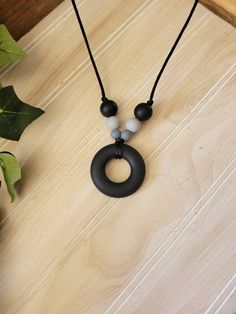 a black and white beaded necklace on a wooden table next to a potted plant